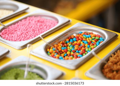 Different candy toppings are on display at a dessert station.