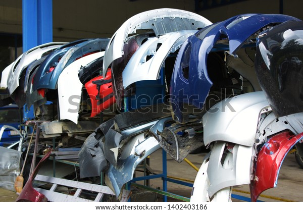Different car bumpers at\
a car paint shop waiting their turn. Different types of bumpers and\
various colors. 
