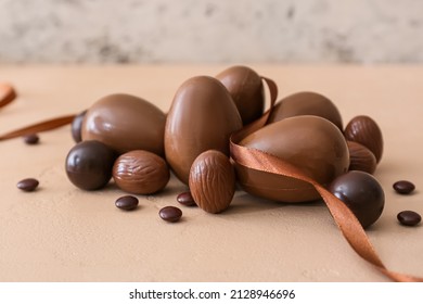 Different chocolate Easter eggs, candies and ribbon on color background