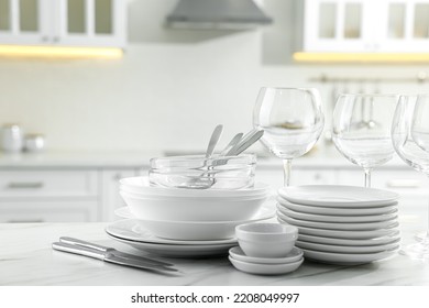 Different clean dishware, cutlery and glasses on white marble table in kitchen - Shutterstock ID 2208049997