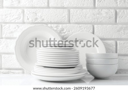 Different clean dishware on white table near brick wall