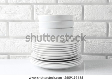 Different clean dishware on white table near brick wall