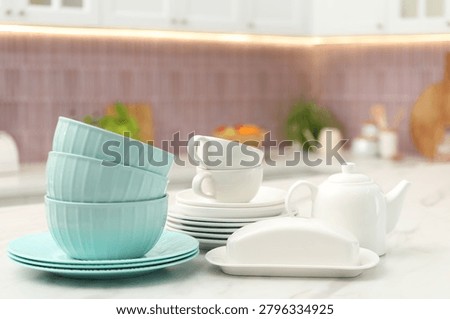 Different clean dishware on white table in kitchen. Space for text