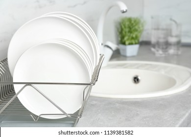 Different clean plates in dish drying rack on kitchen counter - Shutterstock ID 1139381582