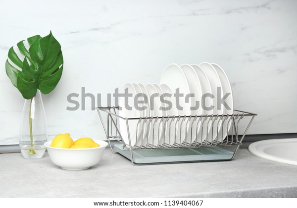 Different clean plates in dish drying rack on\
kitchen counter