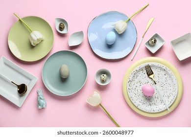 Different clean plates with Easter eggs, toy bunny and beautiful tulip flowers on pink background