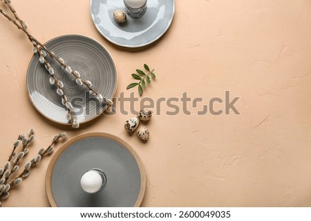 Different clean plates with Easter eggs, fresh leaves and pussy willow branches on beige background