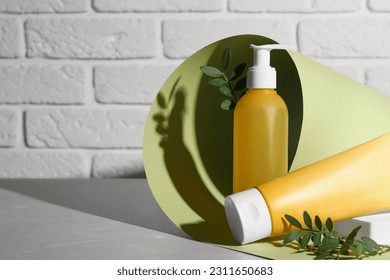 Different cleansers and leaves on grey table, space for text. Cosmetic product - Shutterstock ID 2311650683