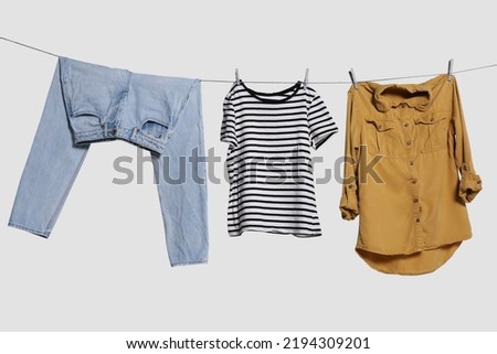 Different clothes drying on laundry line against light background