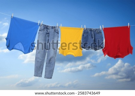 Different clothes drying on washing line against blue sky