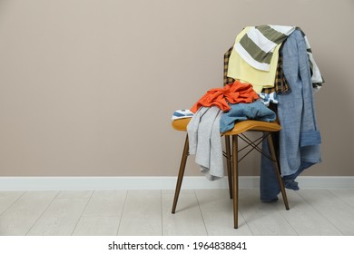 Different clothes on chair near light grey wall, space for text - Shutterstock ID 1964838841