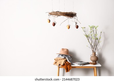 Different Clothes, Tree Branches On Table And Stylish Easter Decor Near Light Wall