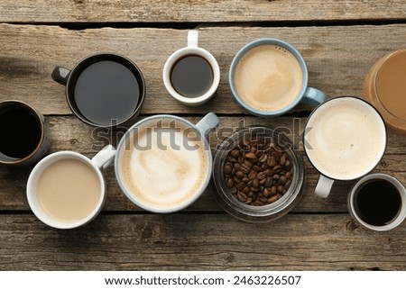 Different coffee drinks in cups and beans on wooden table, flat lay