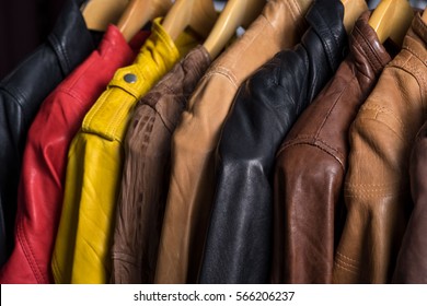 Diferente casaca de cuero colgada en el rack sobre fondo blanco