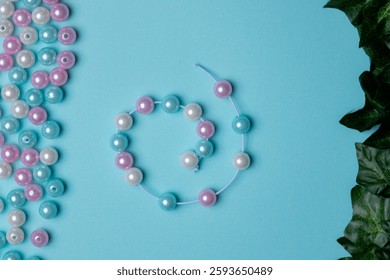 Different colored beads are spread across a blue background, with a completed bracelet made from matching beads laid out nearby.