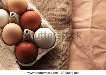 different colored chicken eggs in a box on a burlap background, easter