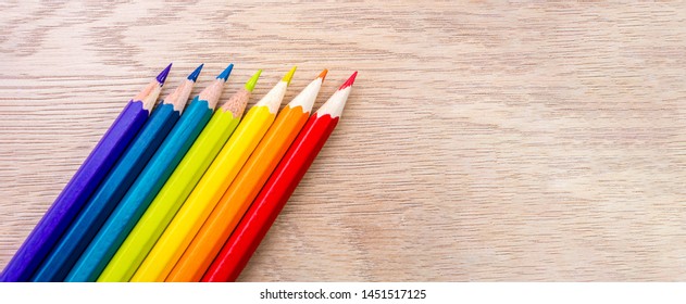 Different colored pencils photo with space for text. Seven pencils of rainbow colors lie on the table. Copyspace. Back to school. Wooden background.