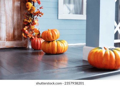 Different colored pumpkins in front door On Wooden Steps. Porch of yard decorated with orange pumpkins in autumn. Thanksgiving. Halloween outside. Residential house decorated for Halloween holiday. 