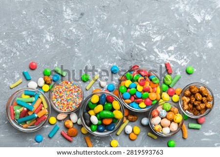 different colored round candy in bowl and jars. Top view of large variety sweets and candies with copy space.