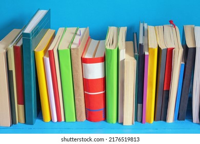 Different Colorful Books On Blue Bookshelf. Copy Space