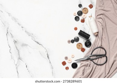 Different colorful buttons with thread spools, scissors and fabric on grunge white background