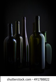 different colorful empty wine bottles family on black background