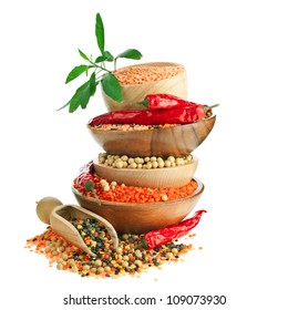 Different colorful lentils in a wooden bowl, soya beans, red chilli peppers with leaves