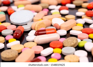 Different colorful pills and capsules. Global pharmaceutical industry for billions dollars per year. Pharmaceutical drugs for use as medications. Studio shot. Macro. Black background.