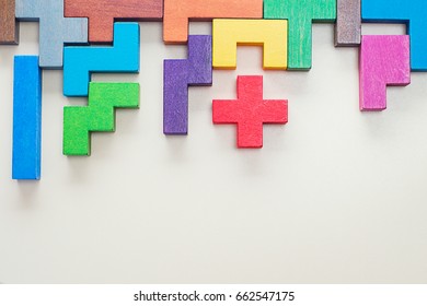 Different colorful shapes wooden blocks on beige background, flat lay. Geometric shapes in different colors, top view. Concept of creative, logical thinking or problem solving. Copy space.