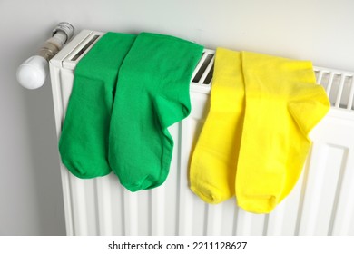 Different Colorful Socks On Heating Radiator Near White Wall