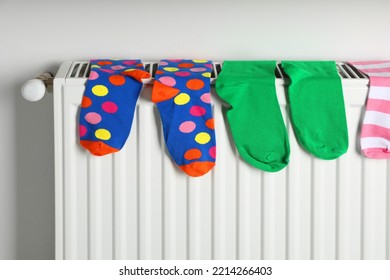 Different Colorful Socks On Heating Radiator Near White Wall