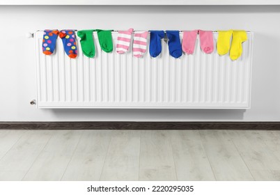 Different Colorful Socks On Heating Radiator Near White Wall