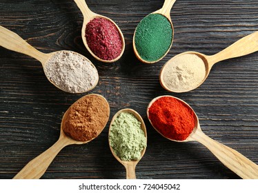 Different Colorful Superfood Powders In Spoons On Wooden Table