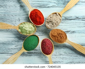 Different Colorful Superfood Powders In Spoons On Wooden Table