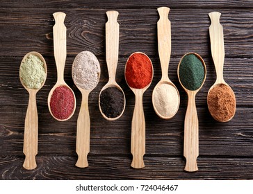 Different Colorful Superfood Powders In Spoons On Wooden Table