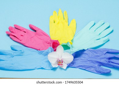 Different Colors Nitrile Disposable Gloves For Personal Protection With An Orchid Flower. Top View. Virus Protective Kit Concept.