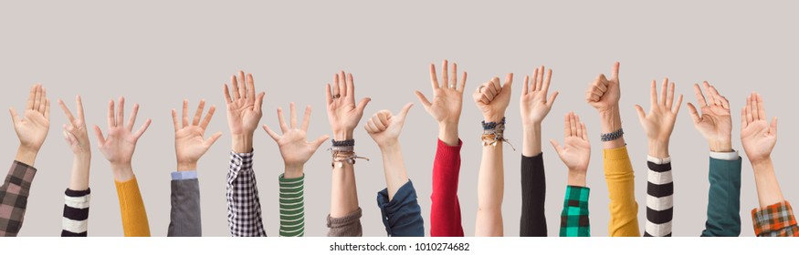 Different colour arms up on gray background - Shutterstock ID 1010274682