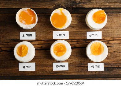 Different cooking time and readiness stages of boiled chicken eggs on wooden table, flat lay