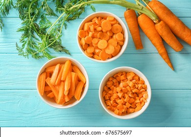Different cuts of carrot in bowls on wooden background