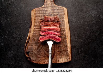 Different degrees of roasting steak on a meat fork on a stone background
