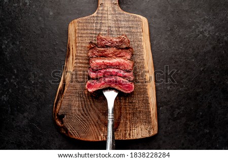Different degrees of roasting steak on a meat fork on a stone background