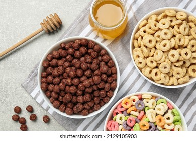 Different delicious breakfast cereals and honey on light grey table, flat lay - Shutterstock ID 2129105903