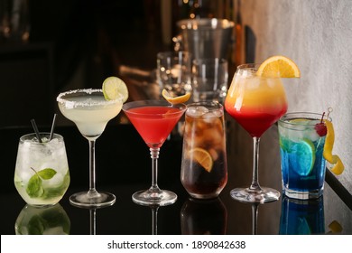 Different delicious cocktails on black table in bar