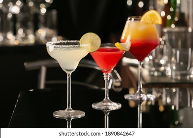 Different delicious cocktails on black table in bar