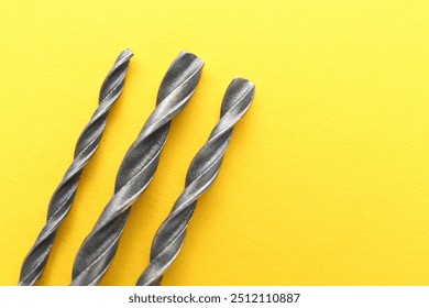 Different drill bits on yellow background, top view. Space for text