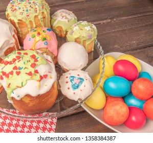 A lot of different easter cakes on the special plate with the multicolour easter eggs on the rustic table