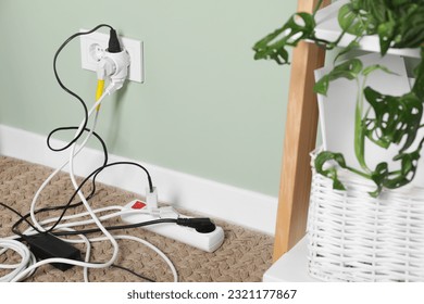 Different electrical plugs in socket and power strip on floor indoors