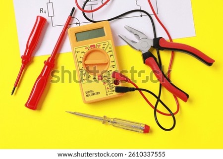 Different electrical tools and circuit diagram on yellow background, flat lay