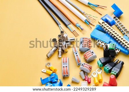 Different electrical tools isolated on yellow background, electrician equipment, wires, terminals, connectors, fuses, switches