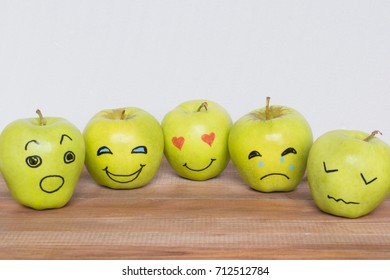 Different emotions drawn on apples, wooden background. 